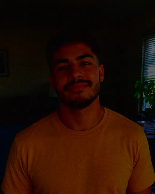 Underexposed photo of a man in a dim room, his face in shadow